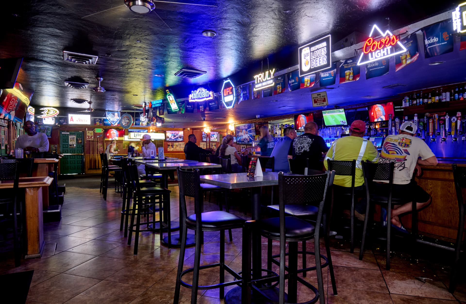 Interior of Harvey's Sports Bar in Anaheim with neon beer signs, TVs and a full bar